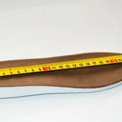 Miarka krawiecka mierzy wkładkę buta o długości około 26 cm.