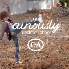 Chłopiec w jesiennych ubraniach kopie liście, z napisem "go curiously back to school" i logo C&A.