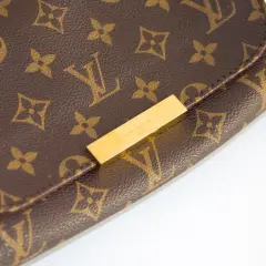 Zbliżenie na brązową torebkę Louis Vuitton z monogramem i złotym zapięciem.