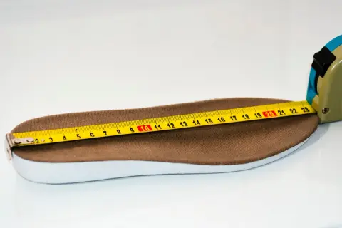 Miarka krawiecka mierzy wkładkę buta o długości około 26 cm.